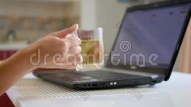 女孩的手，在笔记本电脑键盘上打字，旁边的笔记本电脑-一杯茶。女孩的手拿着一杯茶。